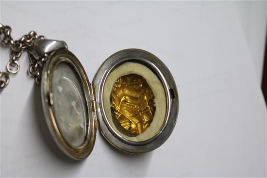 An Indian white and yellow metal oval locket embossed with a deity, on a white metal chain, locket 5cm.